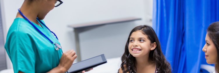 Pediatric Acute Care Nurse Practitioner talking with a little girl and her mom in an urgent care clinic