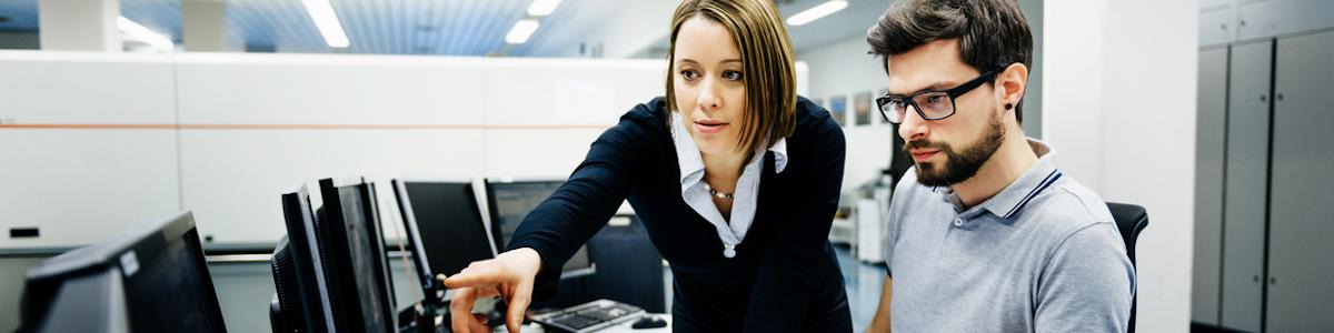 Two cybersecurity professionals looking at a computer monitoring for a system breach