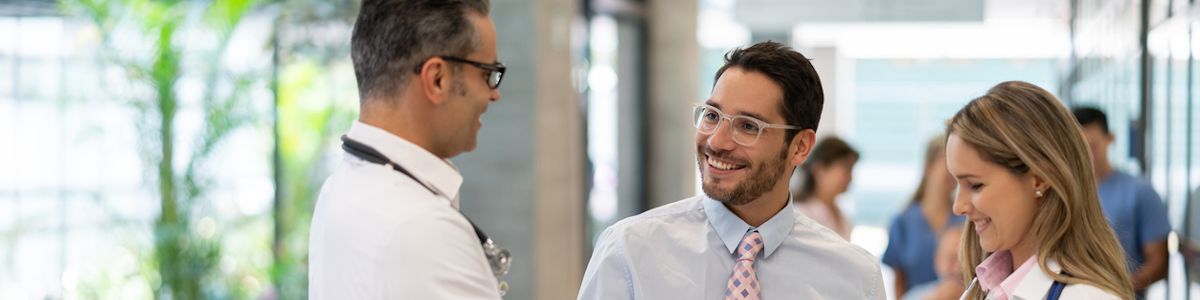 Healthcare administrator talking with two doctors in the hallway of a hospital.