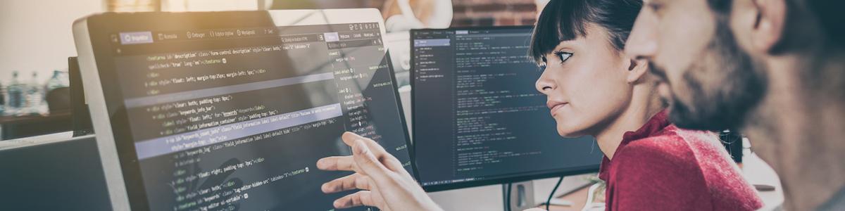 Two software engineers reviewing code on a computer monitor
