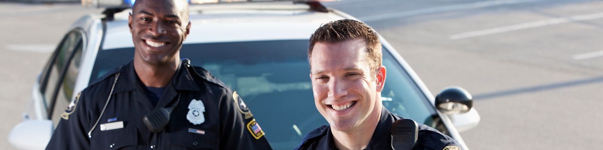 Two law enforcement officers standing near their car smiling