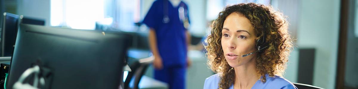 Clinical Nurse Leader making a phone call at a nursing station in a hospital